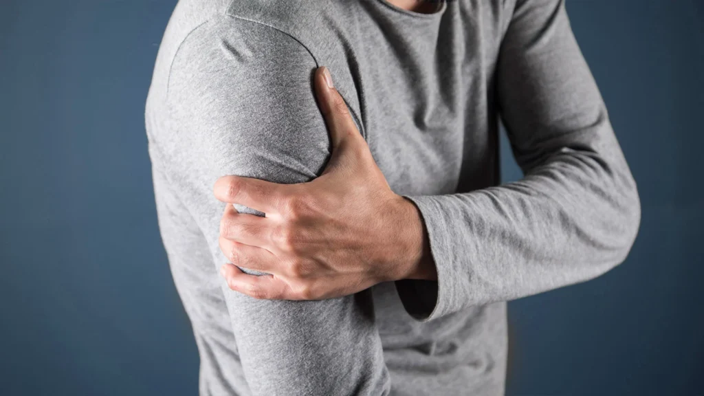 Man Clutching Arm Blue Background