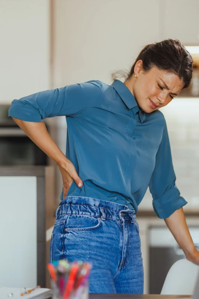 Woman Standing In Kitchen Holding Her Pelvis In Pain